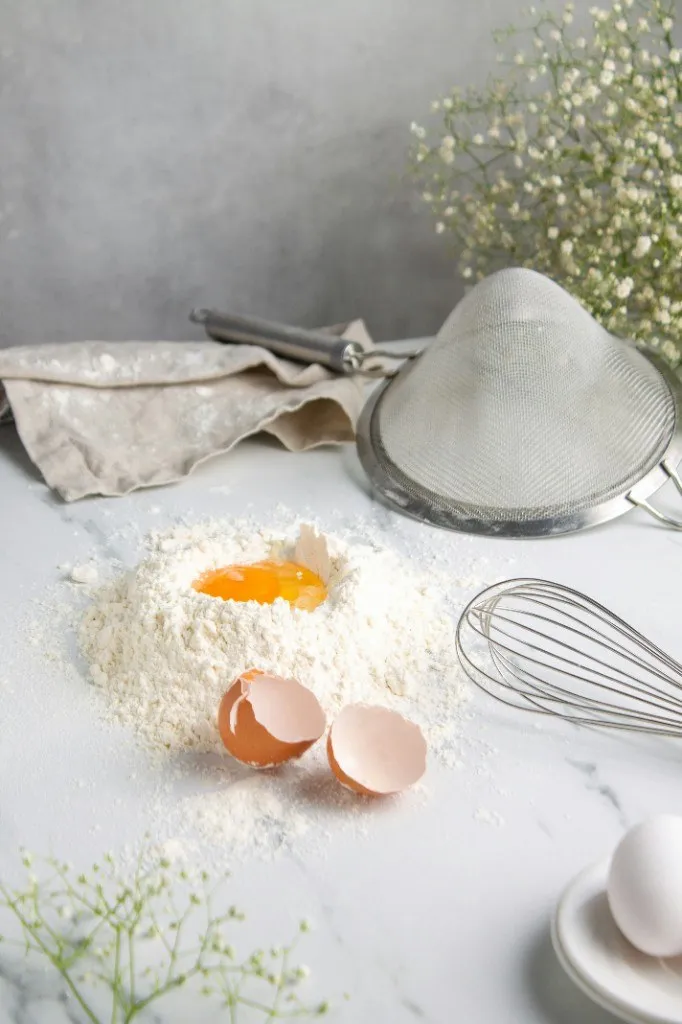 Flour, egg, whisk, and baking tools arranged for homemade cooking