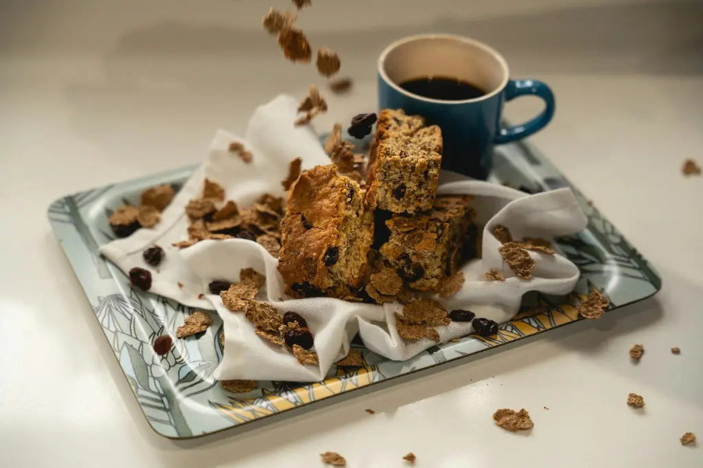 Stack of homemade seed and raisin rusks on a tray beside a cup of coffee