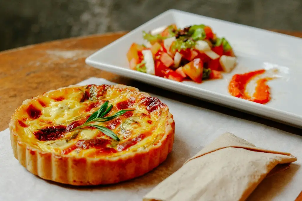 Individual savoury quiche with salad on a wooden table