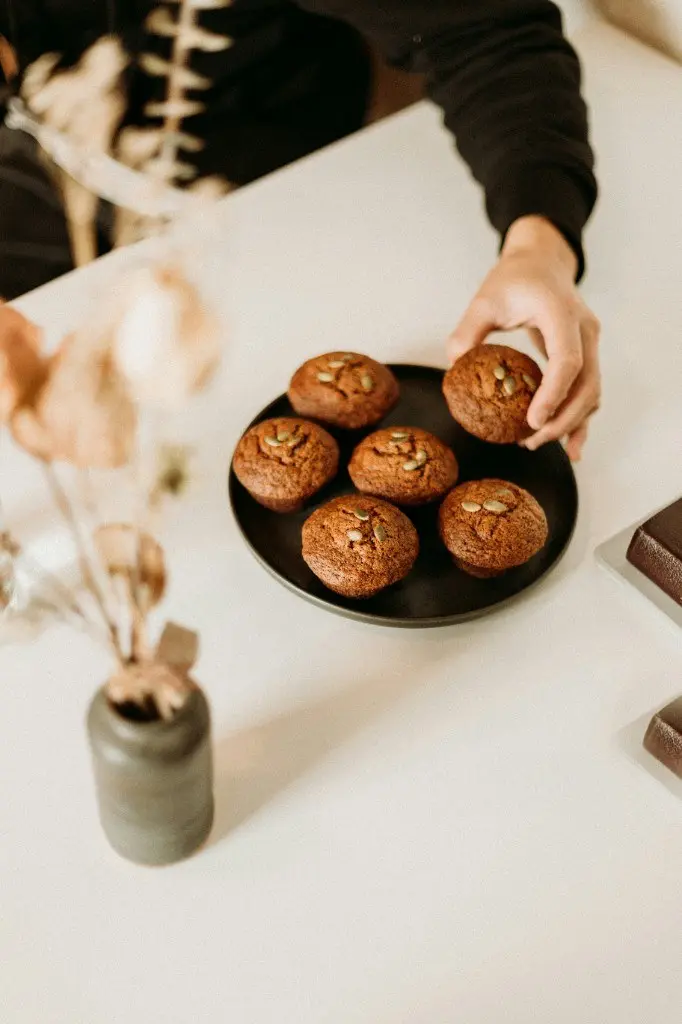 Pumpkin seed muffins on a plate with a hand reaching for one
