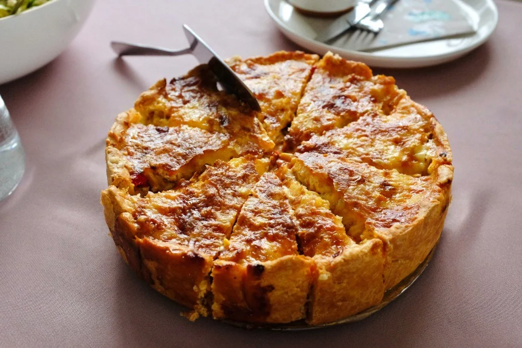 Sliced savoury quiche with golden pastry on a set table
