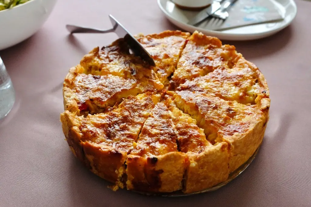 Sliced savoury quiche with golden pastry on a set table