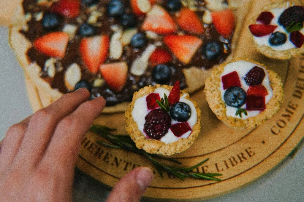 Fruit tarts and a fruit pizza on a wooden serving board